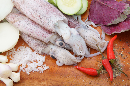 Cooking squids concept. Squids with vegetables on cutting board
