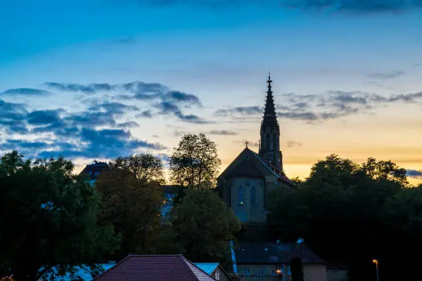 Germany, Beautiful sunset sky decorating medieval ancient church and skyline of stuttgart district berg, called berger church surrounded by trees, seen from above the roofs HDR