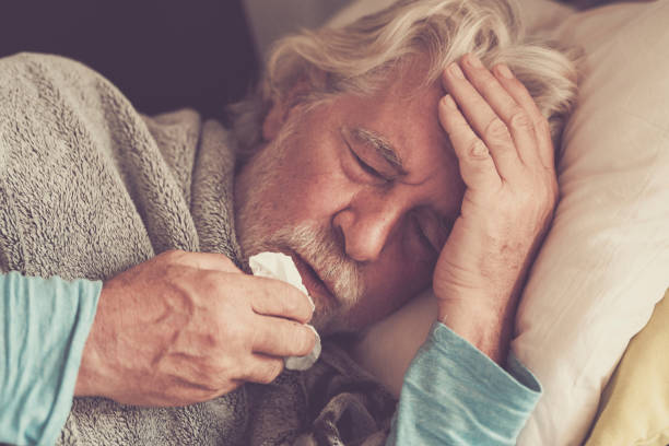Old people senior man with winter seasonal illness fever cold problems drinking a pharmacy medicine or hot tea to go healthy - concept of mature retired with disease