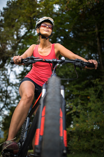 Pretty, young woman riding her mountain bike on a forest path. Enjoying active leisure time outdoors.