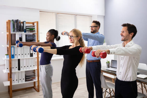 istock Happy Businesspeople Exercising With Dumbbells In Office 1179124729