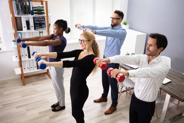 istock Happy Businesspeople Exercising With Dumbbells In Office 1179124736