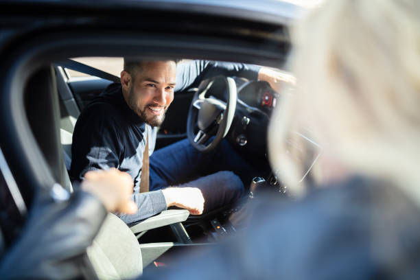 Happy Man Sitting In Car Looking Out Happy Young Man Looking At His Female Friend Standing Outside The Car car pooling stock pictures, royalty-free photos & images