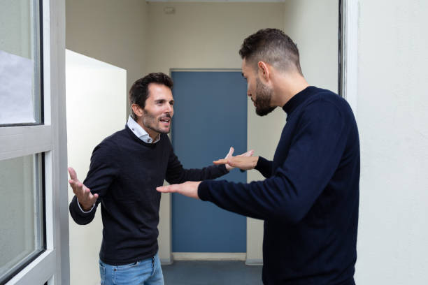 Two Men Quarreling With Each Other Two Young Men Standing At The Door Entrance Quarreling With Each Other neighbour stock pictures, royalty-free photos & images