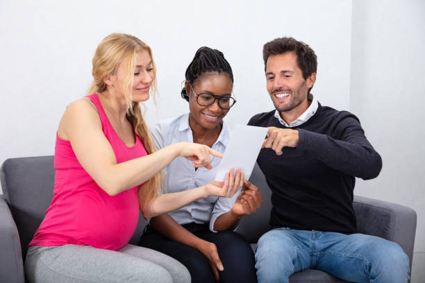 Young Woman Showing Ultrasound Baby Images Surrogate Mother Showing Ultrasound Baby Images To Young Couple surrogacy stock pictures, royalty-free photos & images