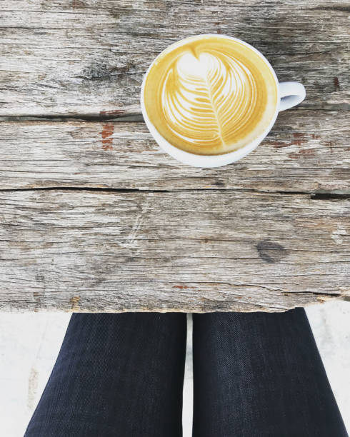 hot latte coffee on natural old wooden table with woman sit near it