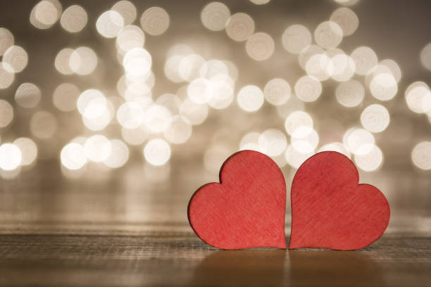 istock Two red hearts on wooden surface with bokeh lights background, on a valentines day concept 1179129846