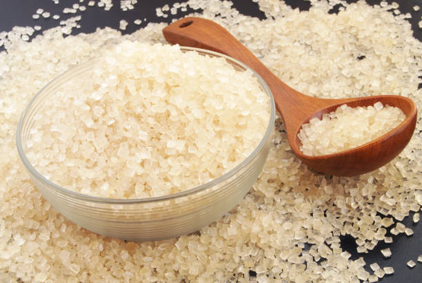 istock Wooden spoon, glass bowl with sugar on black table 1179132329
