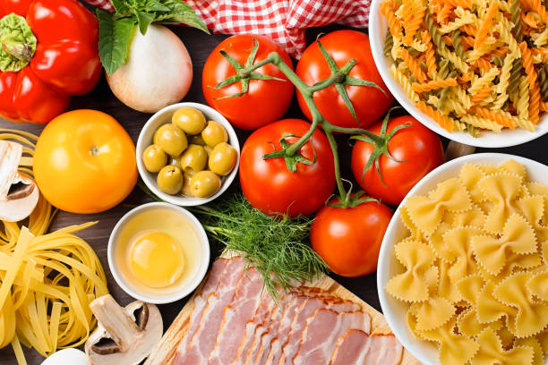 ingredientes de alimentos italianos - pasta, verduras, champiñones, tocino, huevos, aceitunas. estaba plano sobre fondo de madera oscura - 5519 fotografías e imágenes de stock