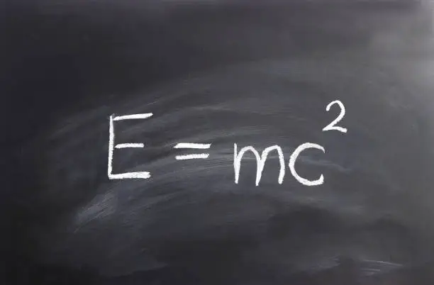 Einstein formula  E= mc2 written on a black chalkboard