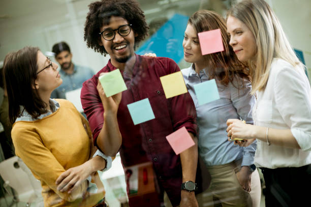istock Young business people discussing in front of glass wall using post it notes and stickers 1179137534