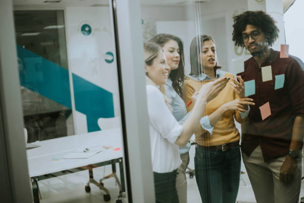 istock Young business people discussing in front of glass wall using post it notes and stickers 1179137537