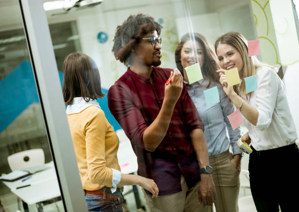 istock Young business people discussing in front of glass wall using post it notes and stickers 1179137539