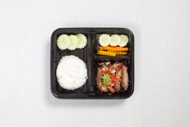 istock Fried Pork with Garlic and Pepper and rice put in black plastic box, put on a white tablecloth, food box, Thai food. 1179137666
