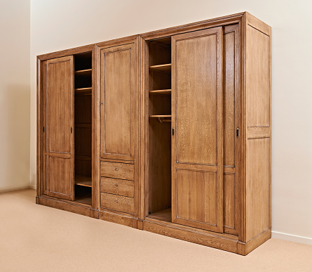Opened classical honey color wooden wardrobe against textured wall