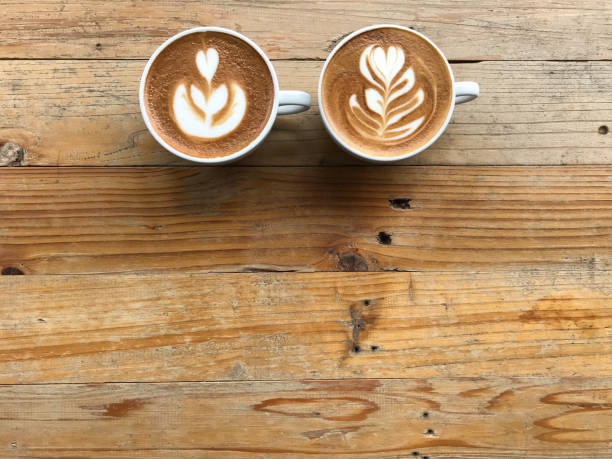 istock hot latte and another of cappuccino coffee with two different latte art, put on grunge pattern wood table 1179143422