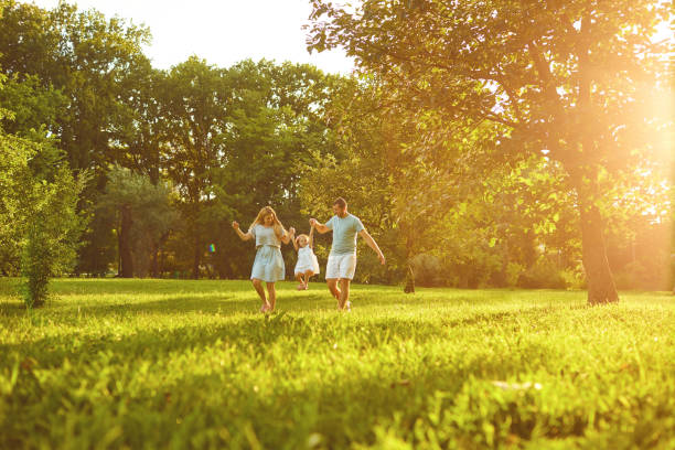 Parents with baby stands on grass in the park