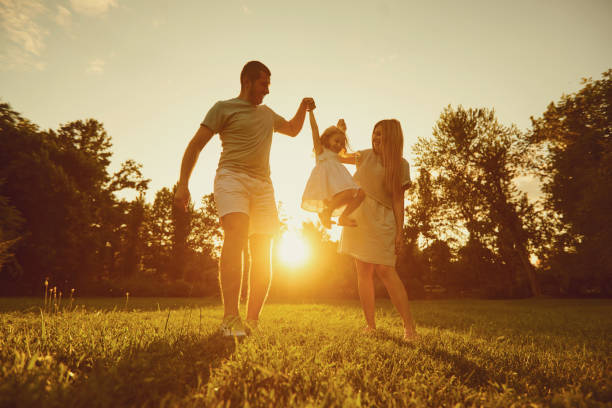 famille jouant avec un enfant au coucher du soleil sur la nature - portrait babies and children people nature photos et images de collection