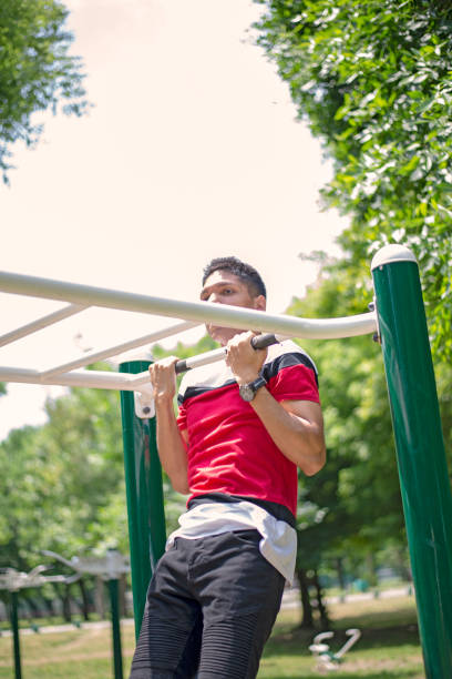 istock Strong athletic young man doing pullups in a public city parkland 1179149151
