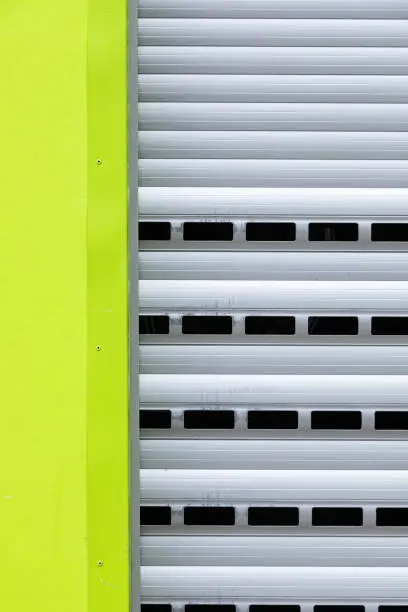 Fragment of roller-shutter door with holes and a part of light green wall
