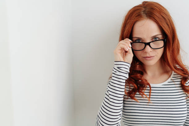 istock Thoughtful young woman peering over her glasses 1179150423