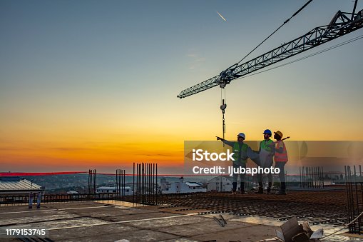 istock Multi ethic workers talking at construction site reviewing plans 1179153745