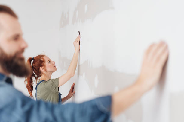 istock Young woman sanding an unpainted clad wall 1179153771