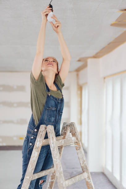 istock Woman replacing bulb while standing on ladder 1179153860