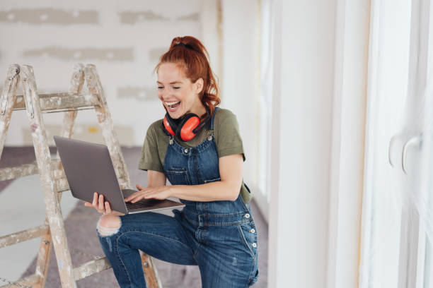 istock Laughing young woman using a handheld laptop 1179153941