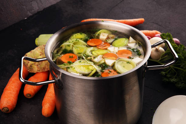 istock Broth with carrots, onions various fresh vegetables in a pot - colorful fresh clear spring soup. Rural kitchen scenery vegetarian broth 1179160868
