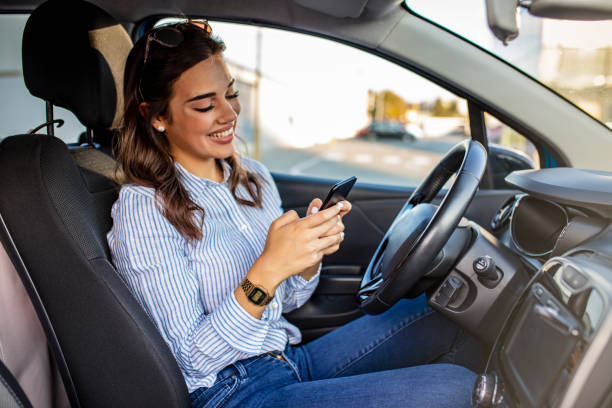 conducteur de femme utilisant un téléphone intelligent dans la voiture. - driving text messaging accident car photos et images de collection