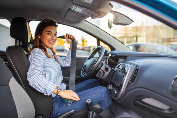 jolie jeune femme conduisant sa nouvelle voiture. - fastening photos et images de collection