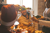 Christmas celebration with champagne - group of friends drinking and toasting together - a hand with bottle pouring sparkling wine in a glass (flute)