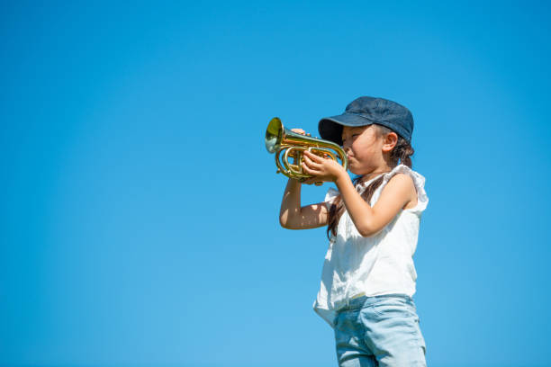 istock Girl playing trumpet under the blue sky 1179165214