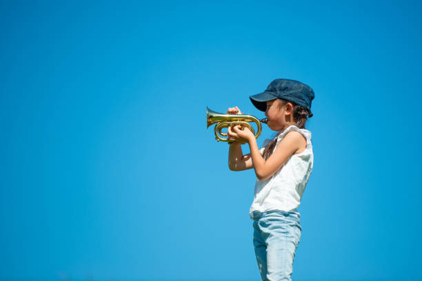 istock Girl playing trumpet under the blue sky 1179165280