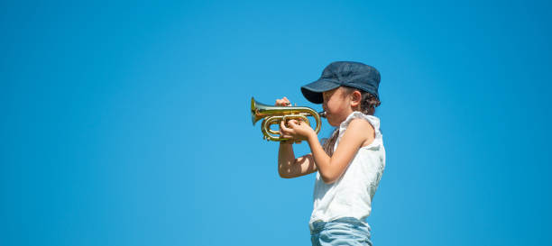 istock Girl playing trumpet under the blue sky 1179165315