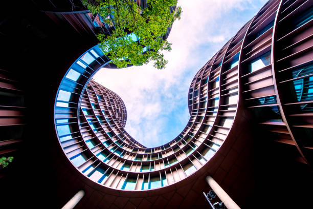 istock Abstract image of a modern building with a dynamic facade and a green tree nearby. 1179165831