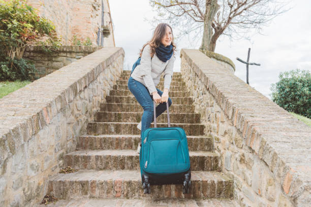 Young woman is going upstairs with her heavy luggage stock photo