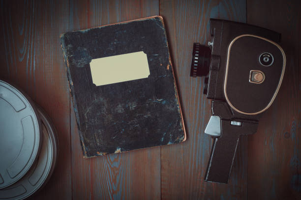 An old movie camera, a box of films and a notebook for notes lie on the table