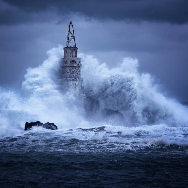 duża fala przeciwko starej latarni morskiej w porcie ahtopol, morze czarne, bułgaria w nastrojowy burzliwy dzień. niebezpieczeństwo, dramatyczna scena. - storm lighthouse cloudscape sea zdjęcia i obrazy z banku zdjęć