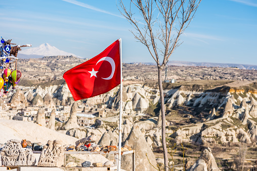 Turkish national flag with background of Goreme town, in Goreme national park. Cappadocia, Turkey