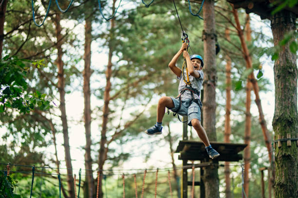 pequeño niño ziplining en el bosque - campamento de verano fotografías e imágenes de stock
