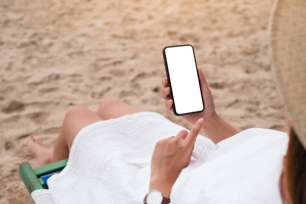 istock a woman holding black mobile phone with blank desktop screen while sitting on a beach chair 1179176705