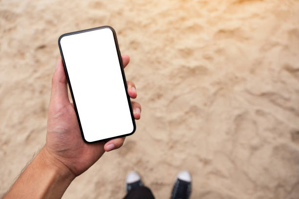 istock a man's hand holding black mobile phone with blank desktop screen while standing on the beach 1179176723