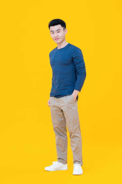 Young cute Asian man standing with hand in pocket gesture isolated on yellow background