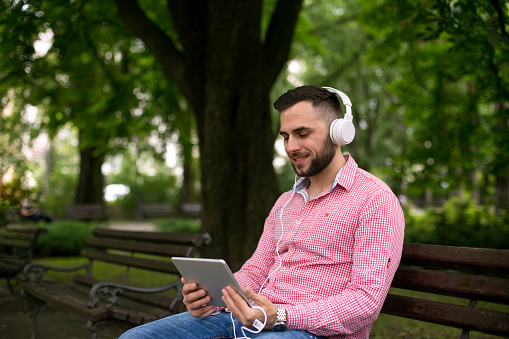 Young man resting at the park and listening music