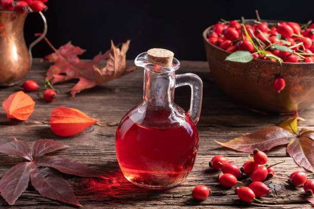 A bottle of rose hip seed oil with fresh rose hips A bottle of rose hip seed oil with fresh rose hips and autumn leaves chinese lantern lily photos stock pictures, royalty-free photos & images