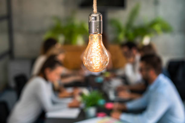 Young creative business people meeting at office. Young business people are discussing together a new startup project. A glowing light bulb as a new idea. business customer engagement stock pictures, royalty-free photos & images