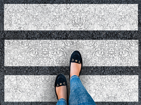 Woman legs crossing the zebra crossing. Top view