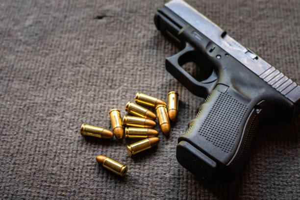 bullets and gun on black velvet desk - handgun gun blue black imagens e fotografias de stock